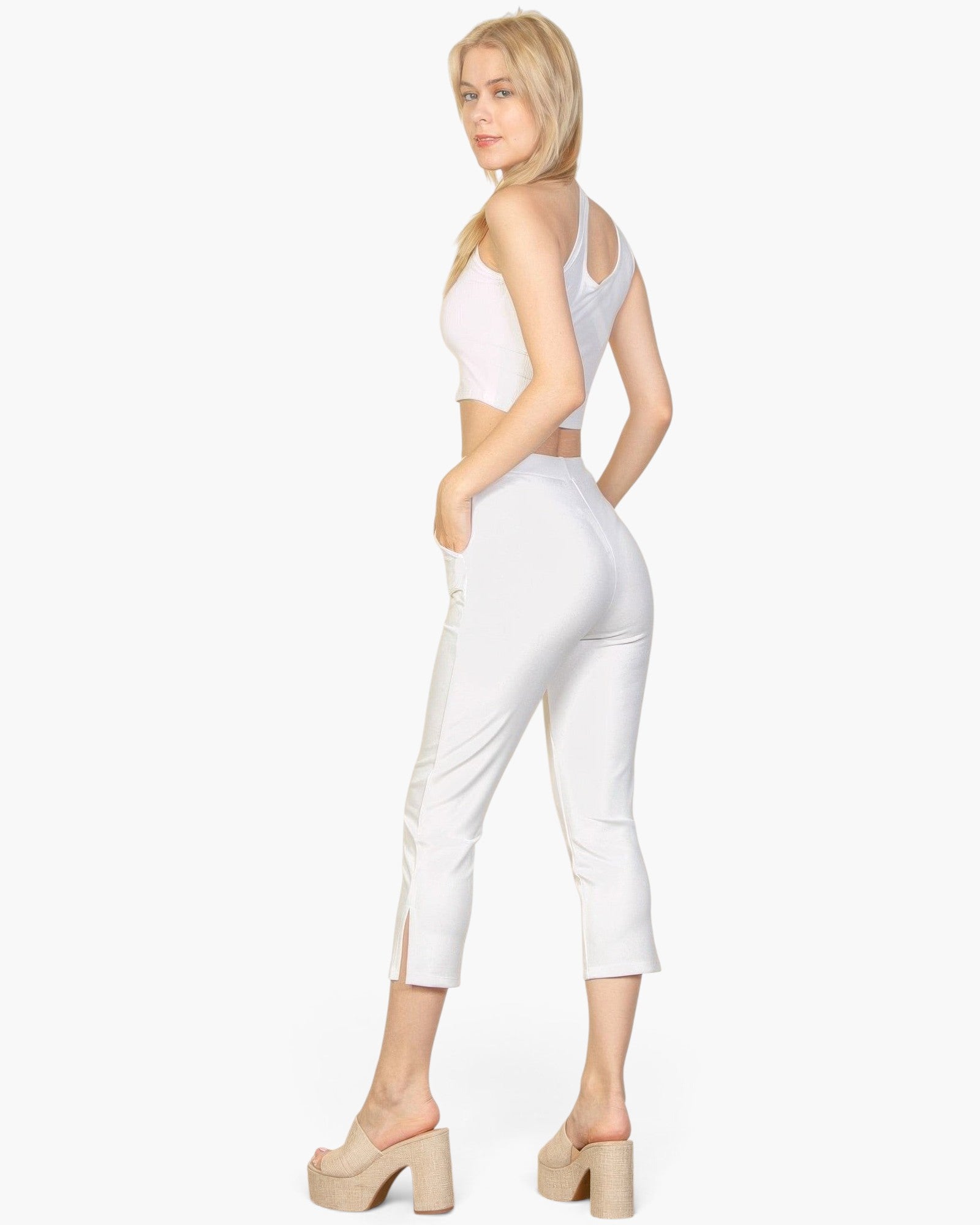 Beach Rose Co. white cropped pants with slit hem detail worn by a blonde model in a white crop top and platform heels