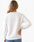 Beach Rose Co. white crew neck sweatshirt with long sleeves and ribbed hem, back view on a blonde model