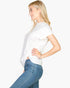 Beach Rose Co. white twist front tee with batwing sleeves worn by a blonde model in profile view with blue jeans