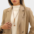 Beach Rose Co. long boho necklace with brown PU cord, wooden beads, and gold-tone accents worn over a beige blazer.
