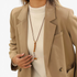 Beach Rose Co. long boho necklace with brown PU cord, wooden beads, and gold-tone accents worn over a beige blazer.