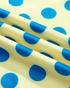 Beach Rose Co. yellow polyester sweatshirt fabric with blue polka dot pattern in a close-up view.