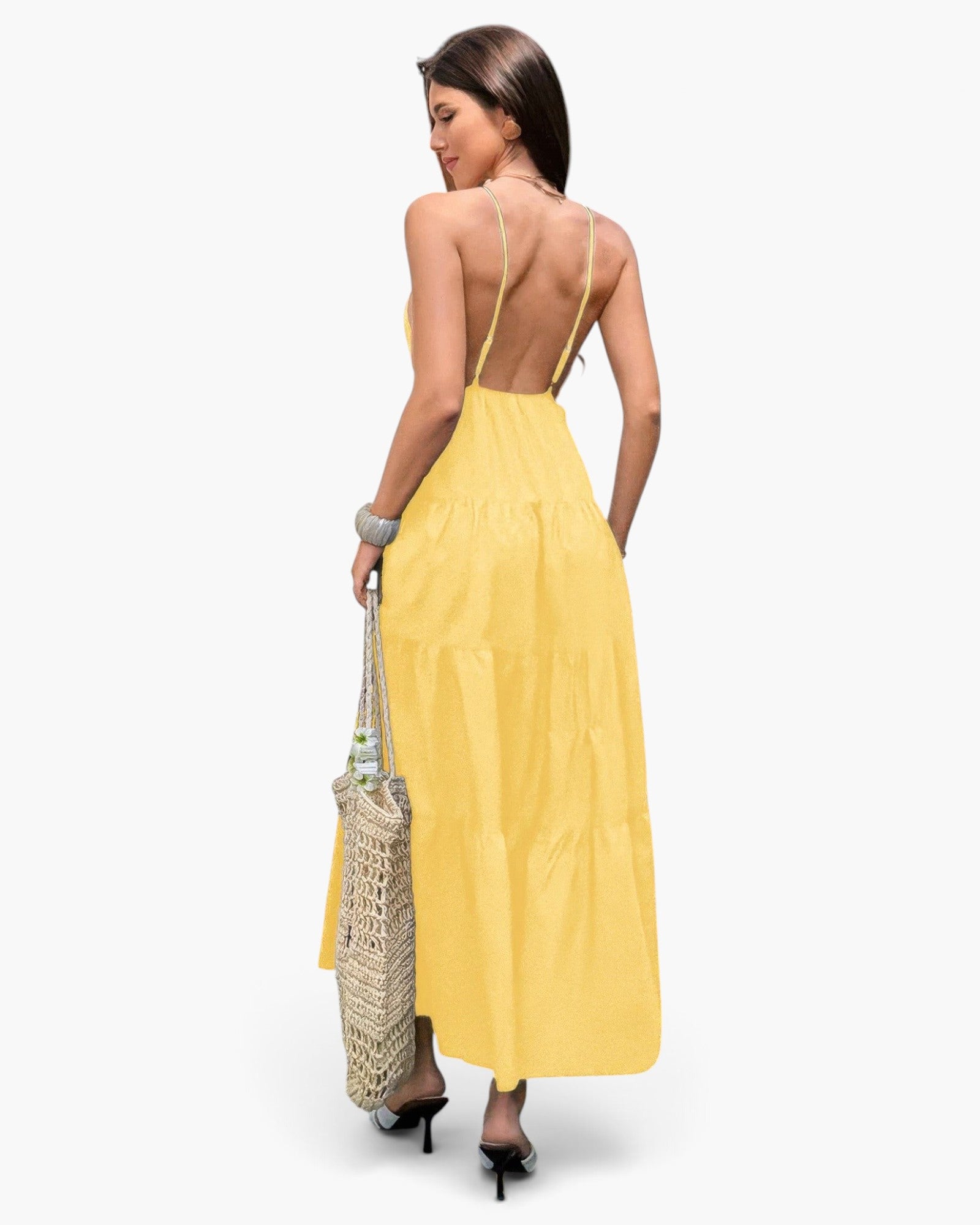 Beach Rose Co. yellow sleeveless maxi dress with an open back and tiered skirt, worn by a woman holding a tote bag.