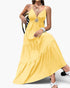 Beach Rose Co. yellow sleeveless maxi dress with a high waist, tiered skirt, and open back detail on a seated model.