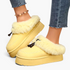 Beach Rose Co. yellow suede platform clogs with plush faux fur trim, moccasin stitching, and decorative tassels.