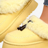 Beach Rose Co. yellow suede platform clogs with plush faux fur trim, moccasin stitching, and decorative tassels.