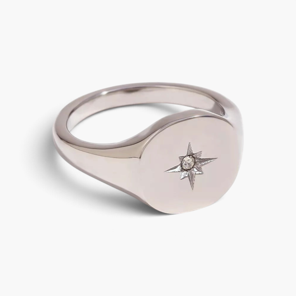 Beach Rose Co. gold-plated signet ring with a rounded face, engraved starburst, and a clear zircon centerpiece.