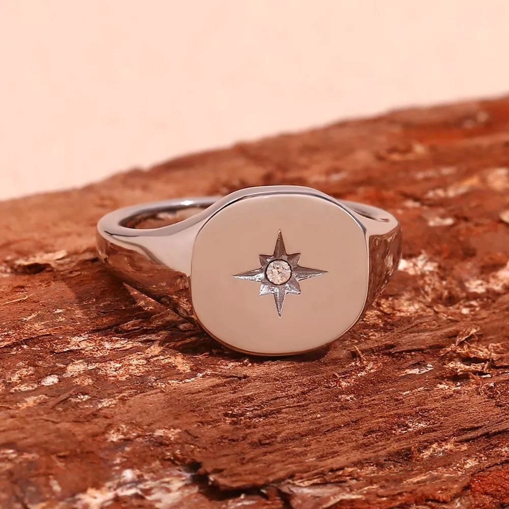Beach Rose Co. gold-plated signet ring featuring a rounded face with an engraved starburst and clear zircon center.