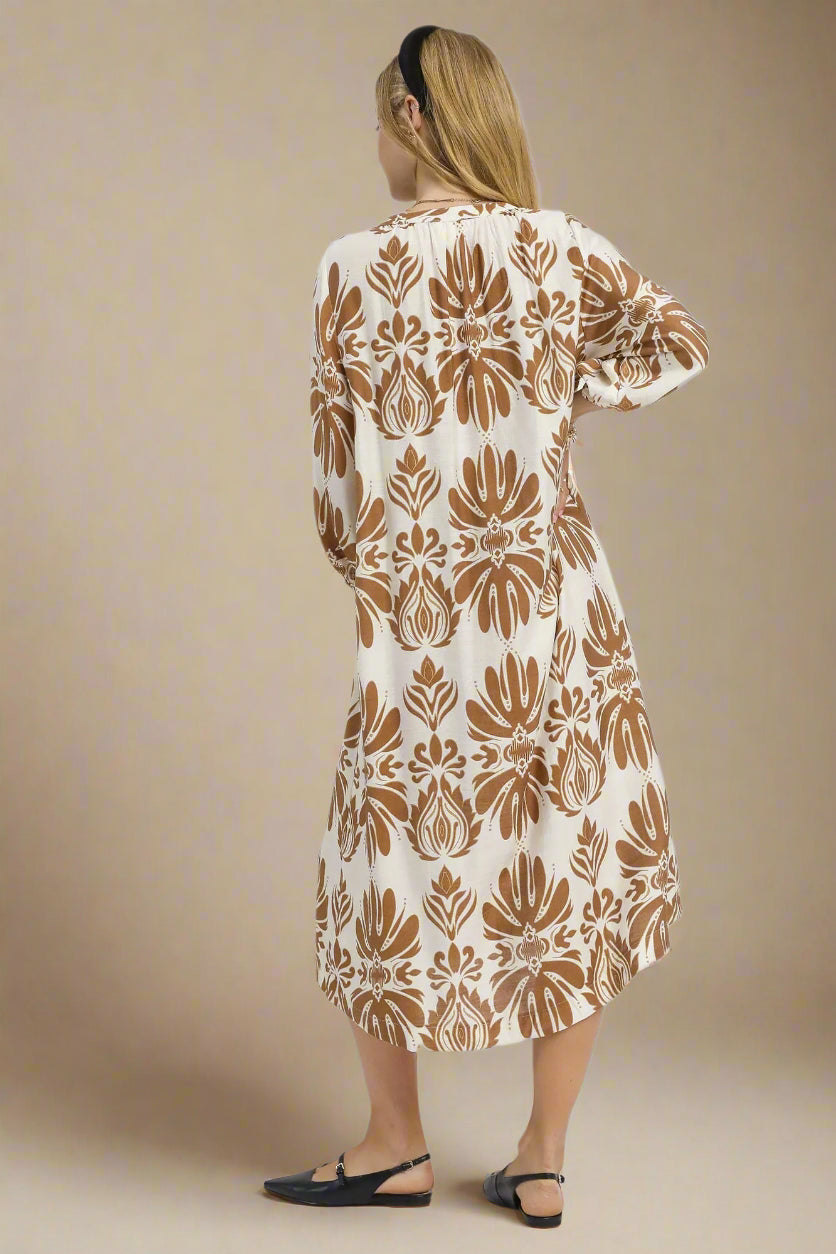 Woman wearing a long, patterned dress with a neutral background