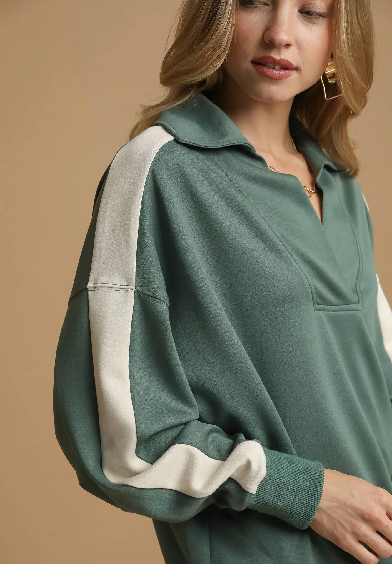 Green and white long-sleeve top worn by a person on a beige background
