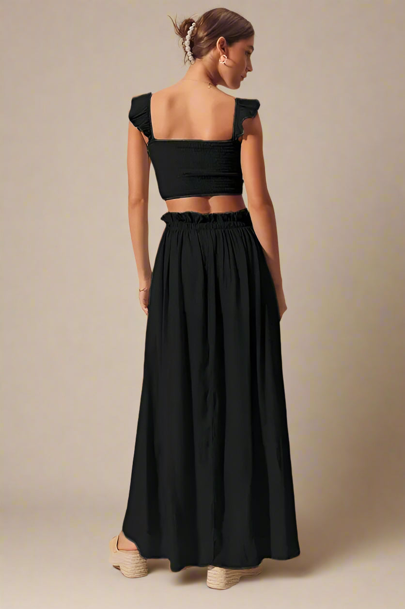 Woman wearing a black maxi skirt set with a plain background