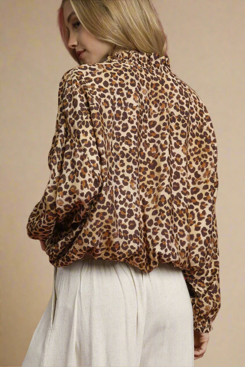 Person wearing a leopard print blouse against a red background