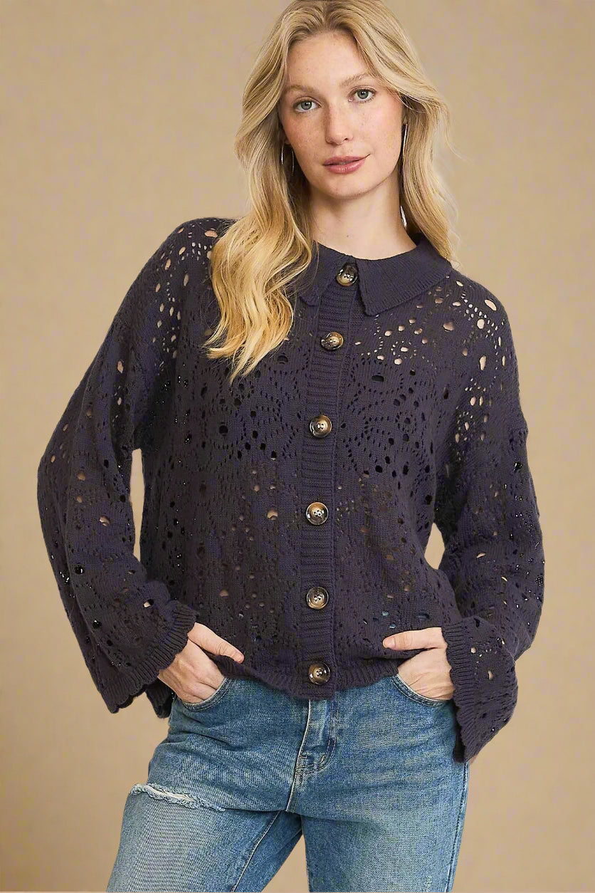 Woman wearing a dark navy cardigan with gold buttons on a beige background