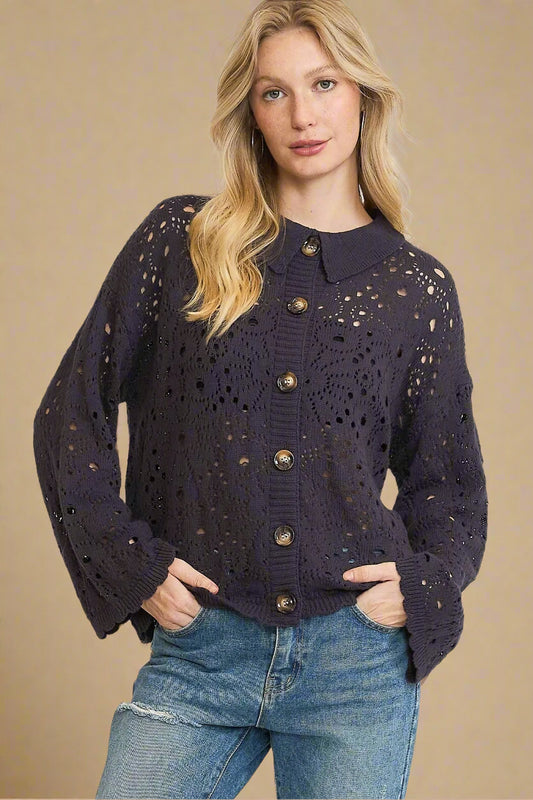 Woman wearing a dark navy cardigan with gold buttons on a beige background