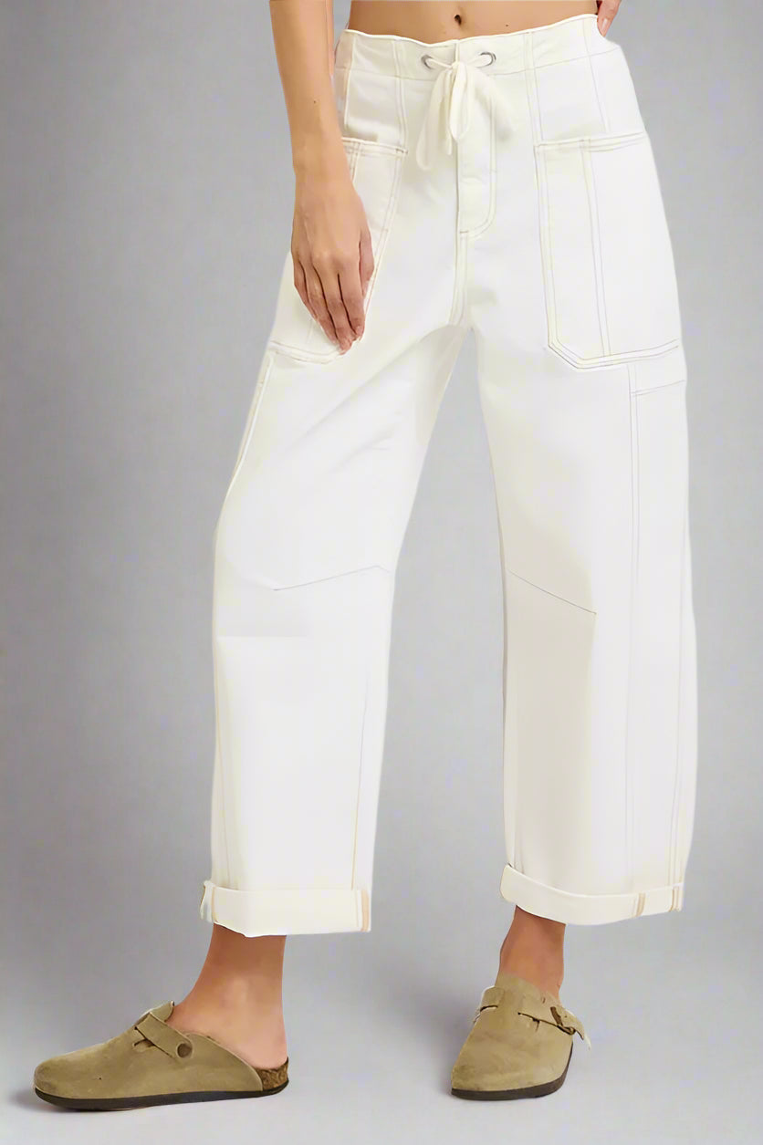 Person wearing white pants with a drawstring waist on a plain background