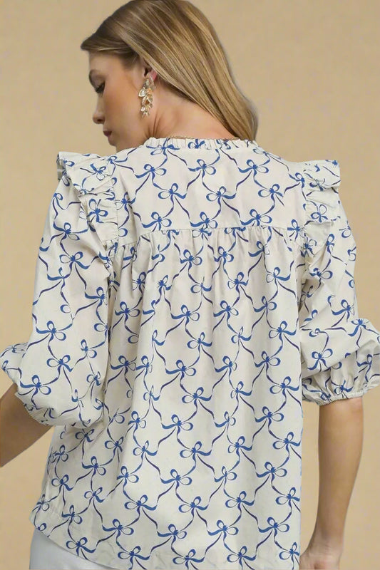 Woman wearing a white blouse with blue bow pattern on a beige background