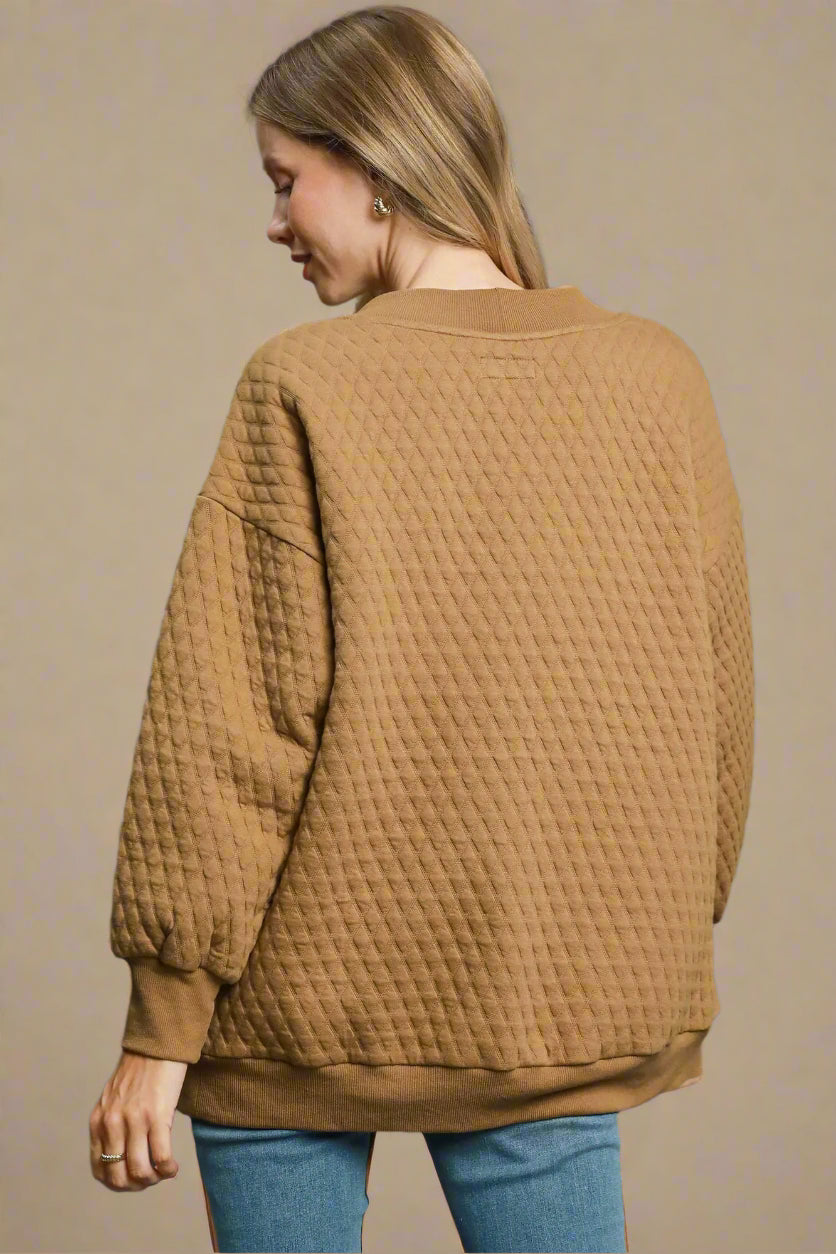 Woman wearing a textured brown sweater on a beige background