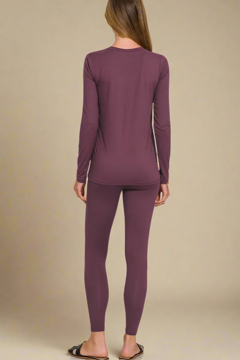 Person wearing eggplant-colored long-sleeve top and leggings on a beige background