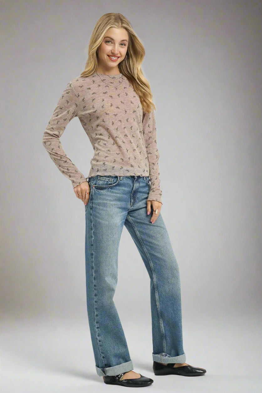 Woman wearing a beige long-sleeve top and blue jeans on a white background