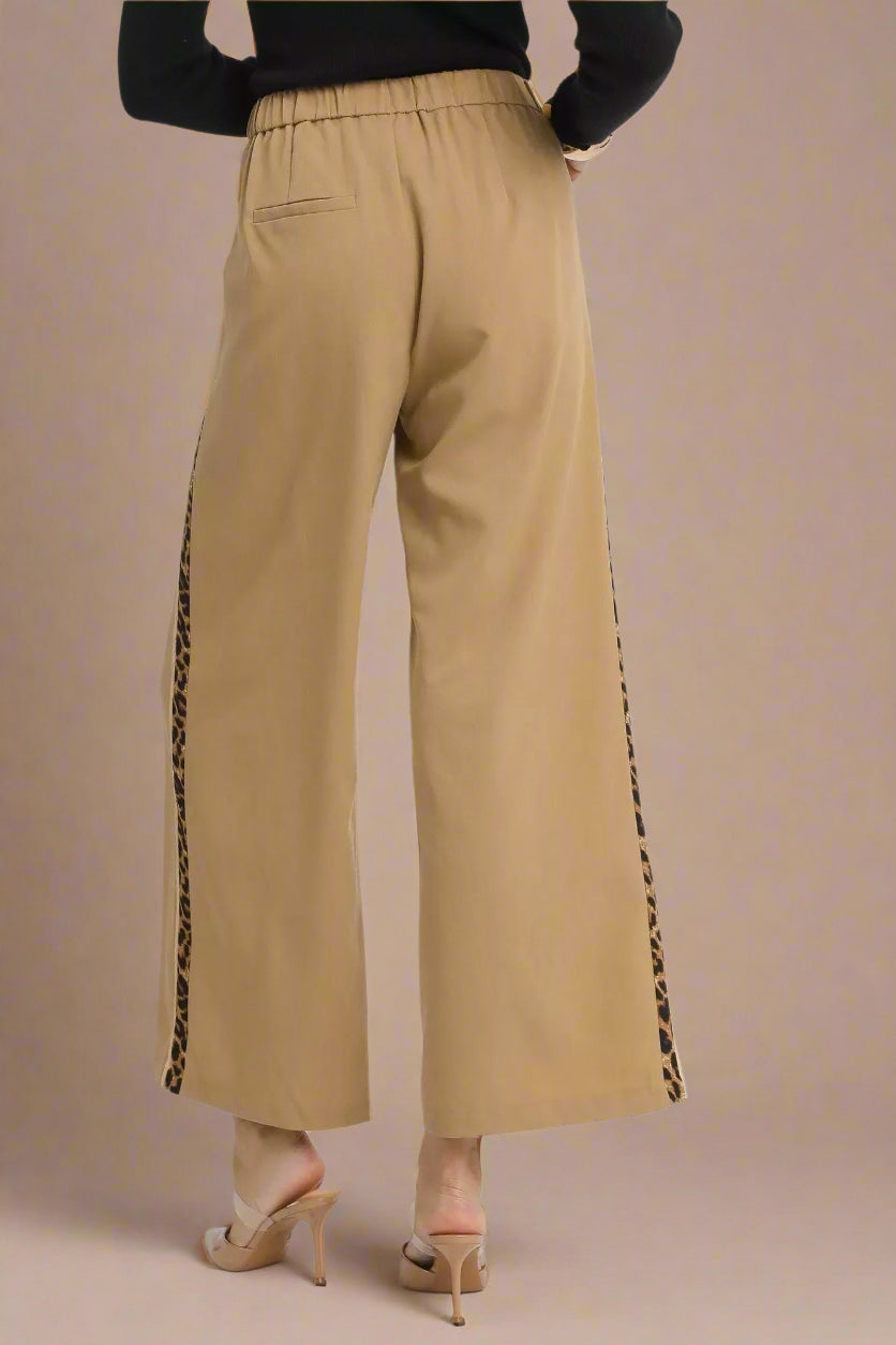 Beige pants with black side stripes on a white background