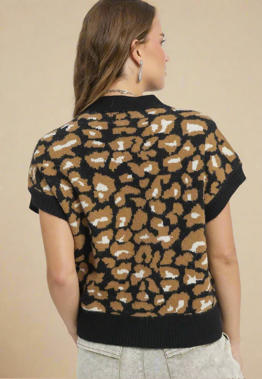 Woman wearing a leopard print sweater with black trim on a beige background