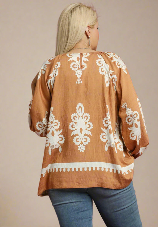 Woman wearing a brown blouse with white patterns on a beige background