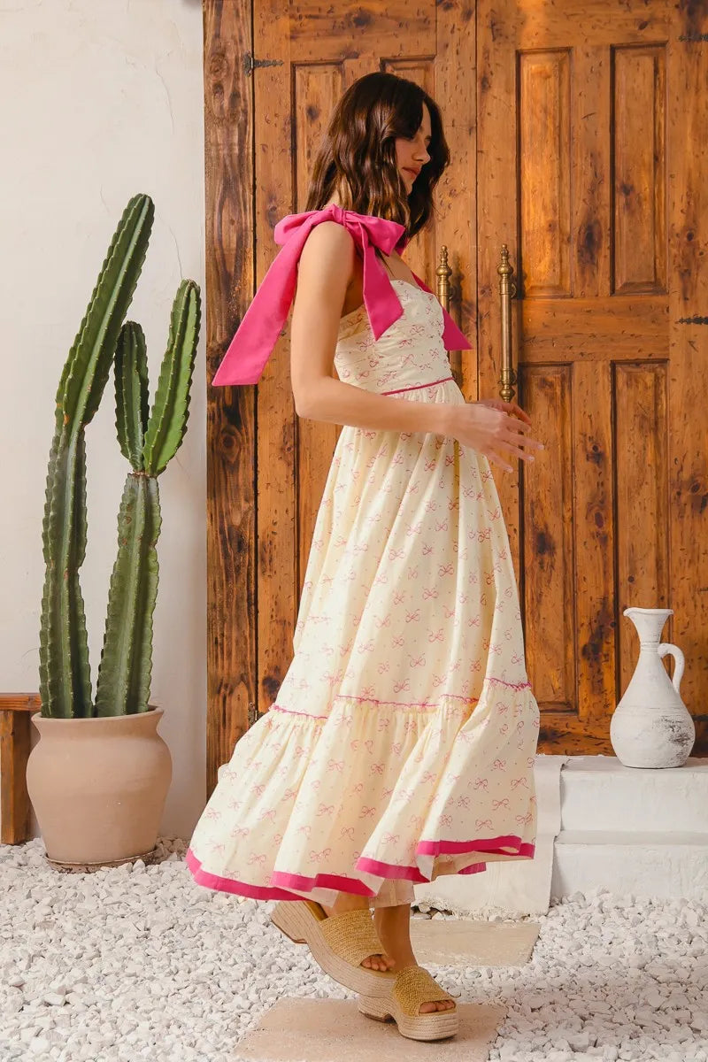 Woman in a white dress with pink accents standing in a room with a wooden door and cactus plant.