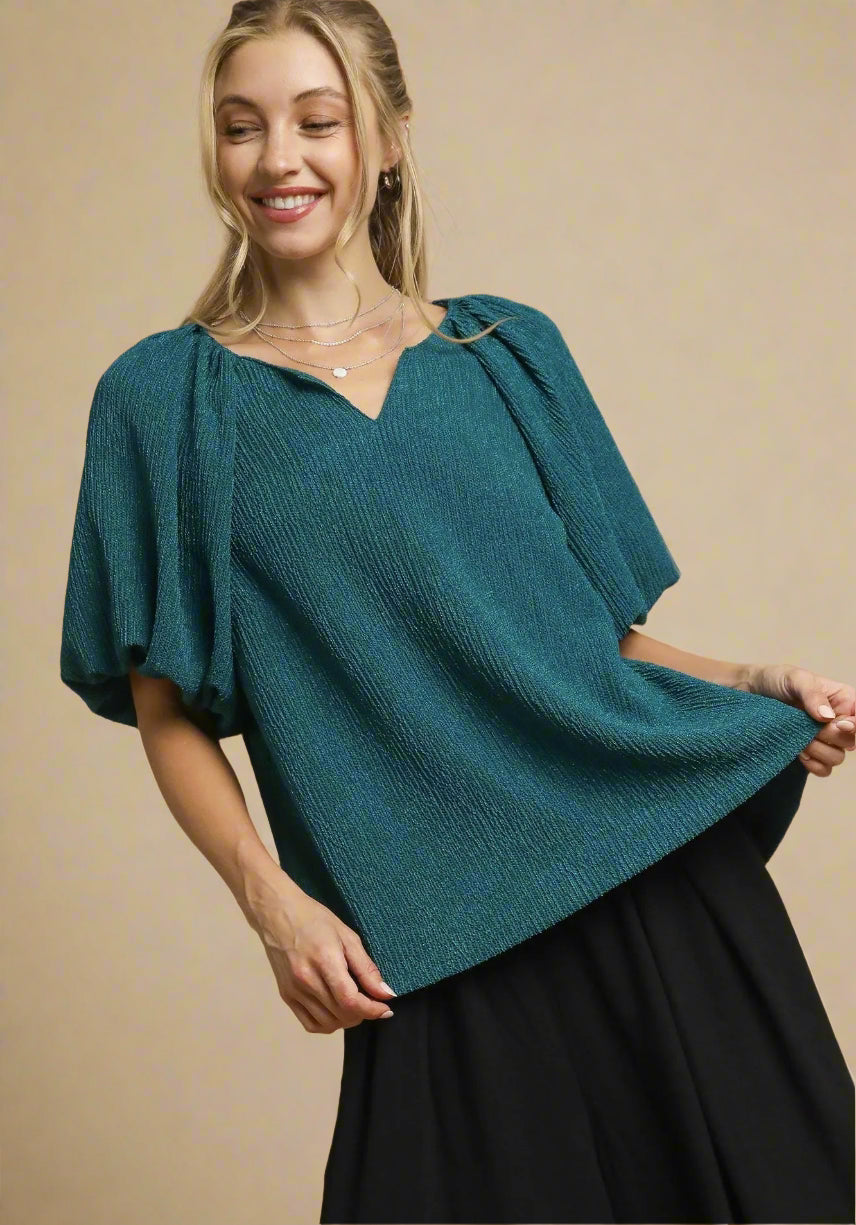 Woman wearing a teal knitted top against a beige background