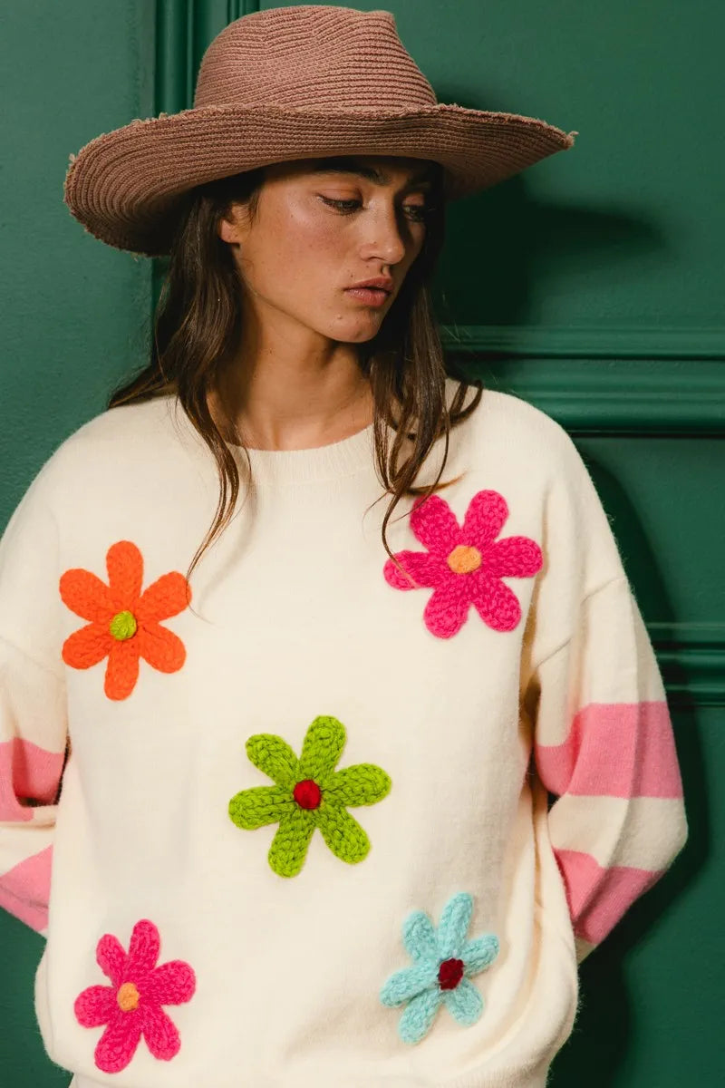 Woman wearing a sweater with colorful flower patterns against a green background