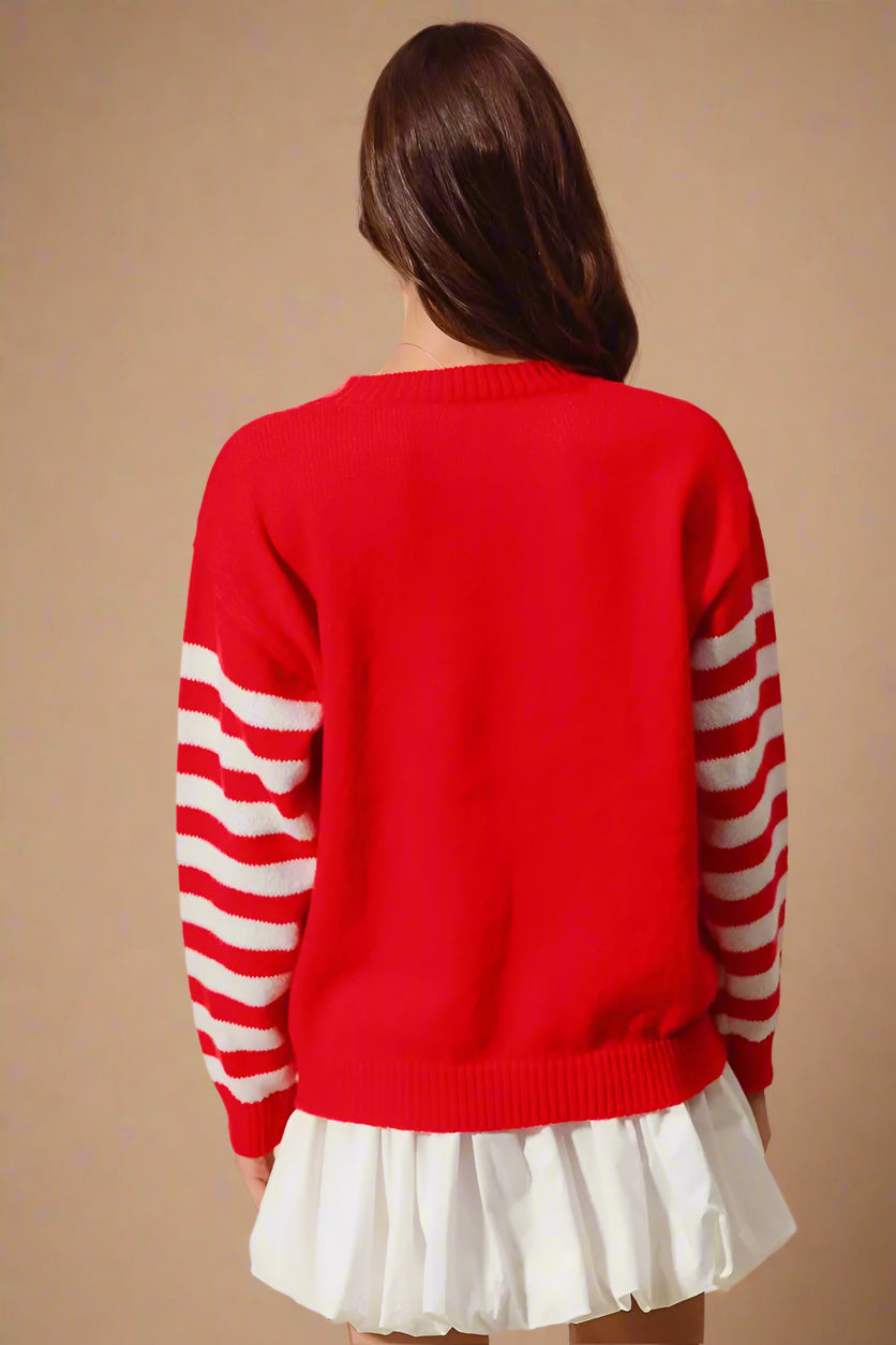 Person wearing a red sweater with white striped sleeves on a beige background