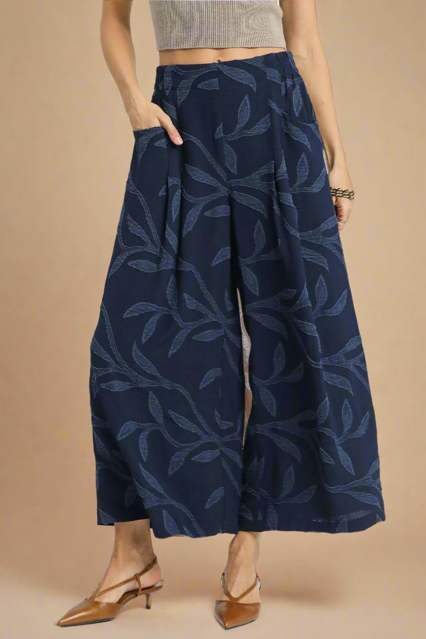 Navy wide-leg pants with leaf pattern worn by a person on a white background