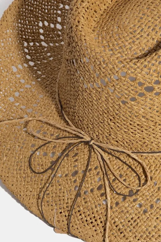 Close-up of a straw hat with a decorative bow on a white background