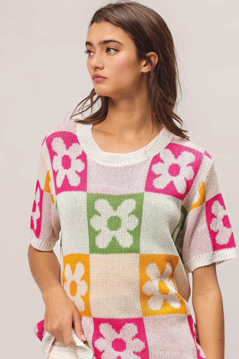 Woman wearing a colorful knit sweater with flower patterns on a plain background