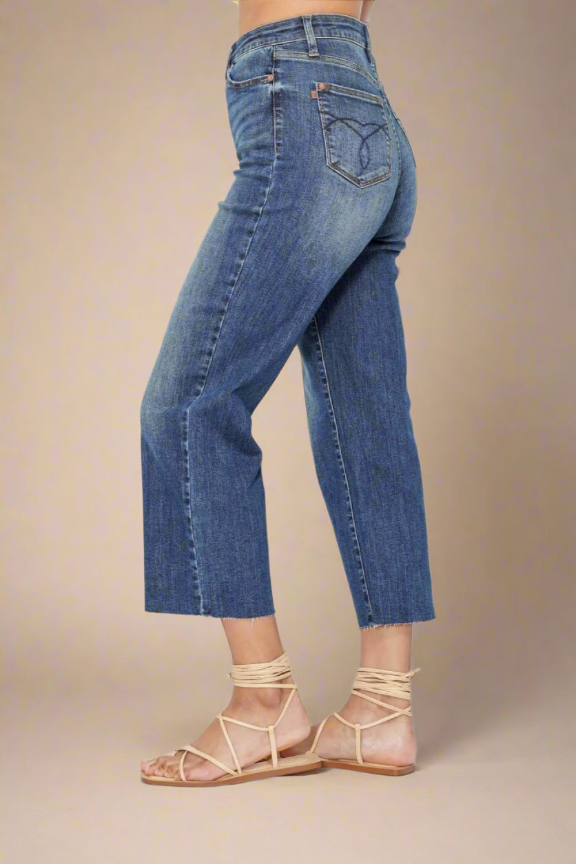 Person wearing blue jeans and beige sandals on a beige background