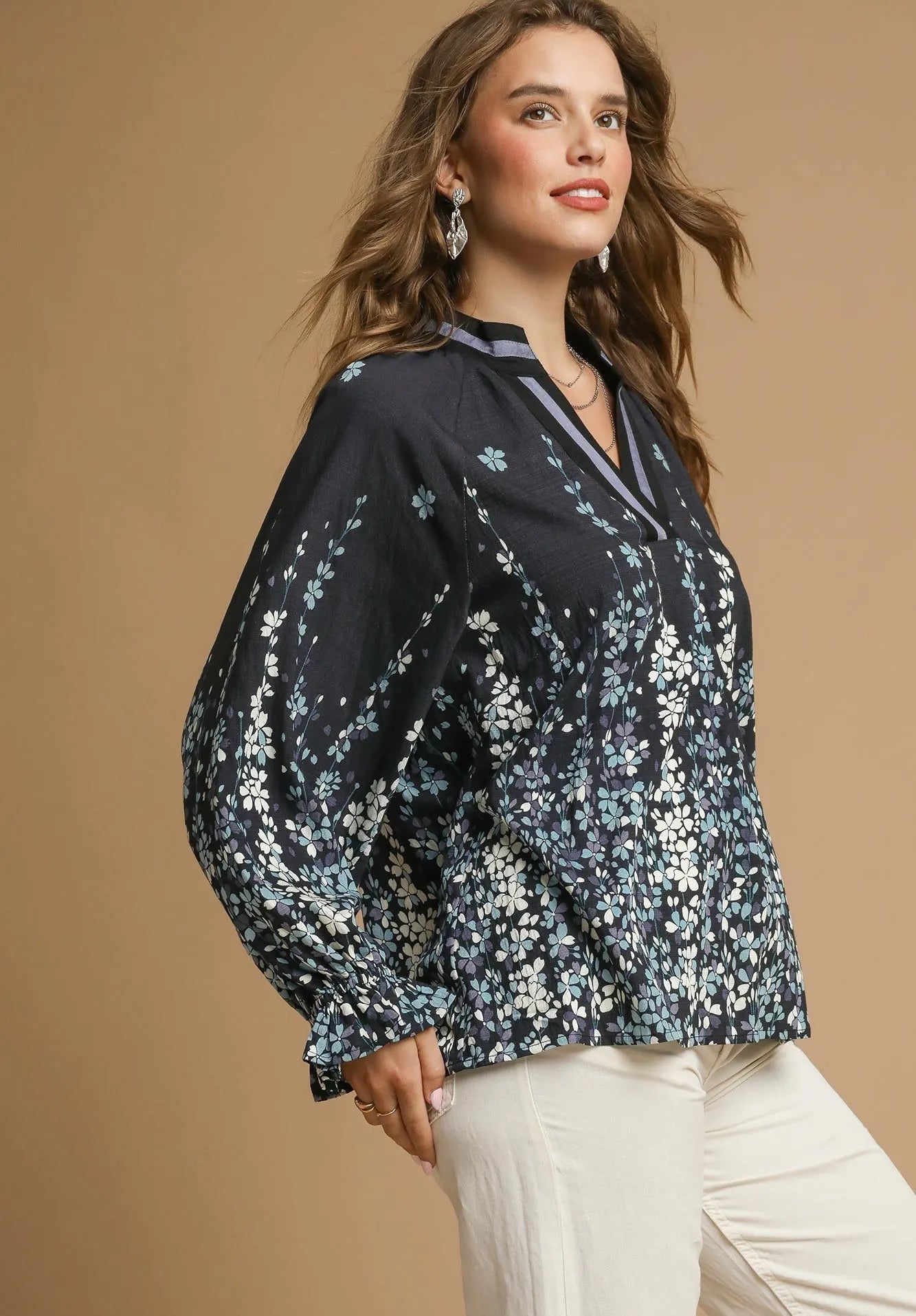 Woman wearing a black floral blouse against a beige background