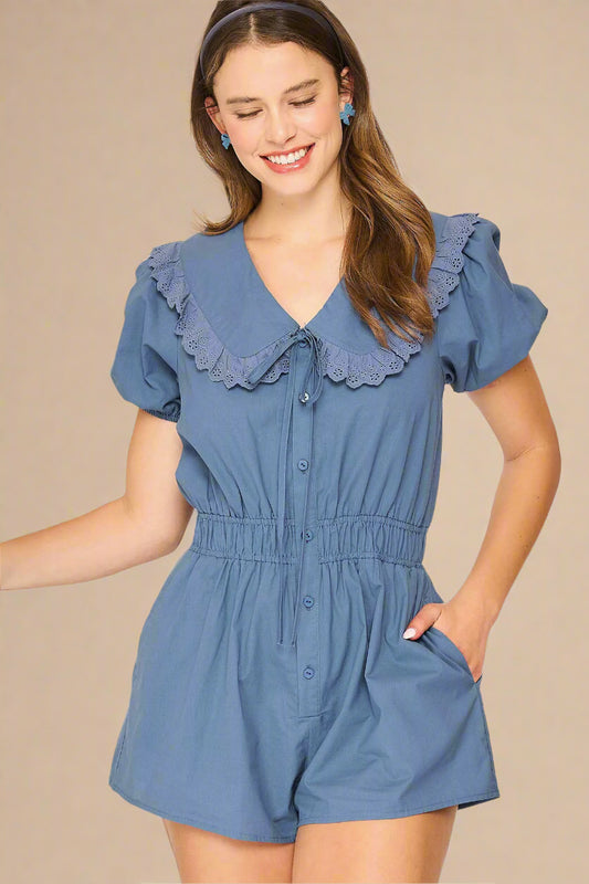 Woman wearing a blue romper with ruffled collar on a light background