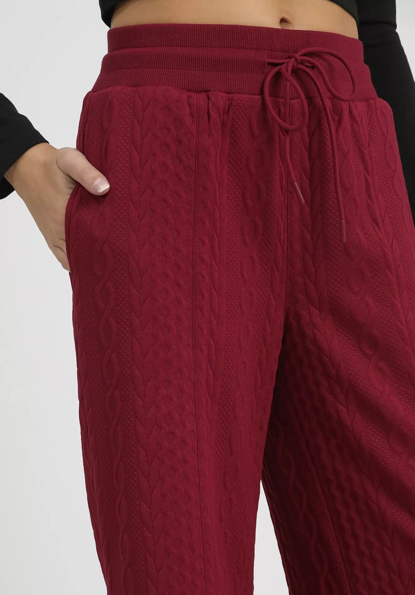Burgundy textured pants with a drawstring waist on a white background