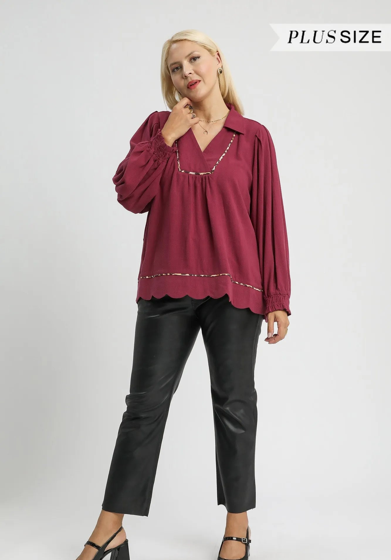 Woman wearing a burgundy blouse and black pants on a white background