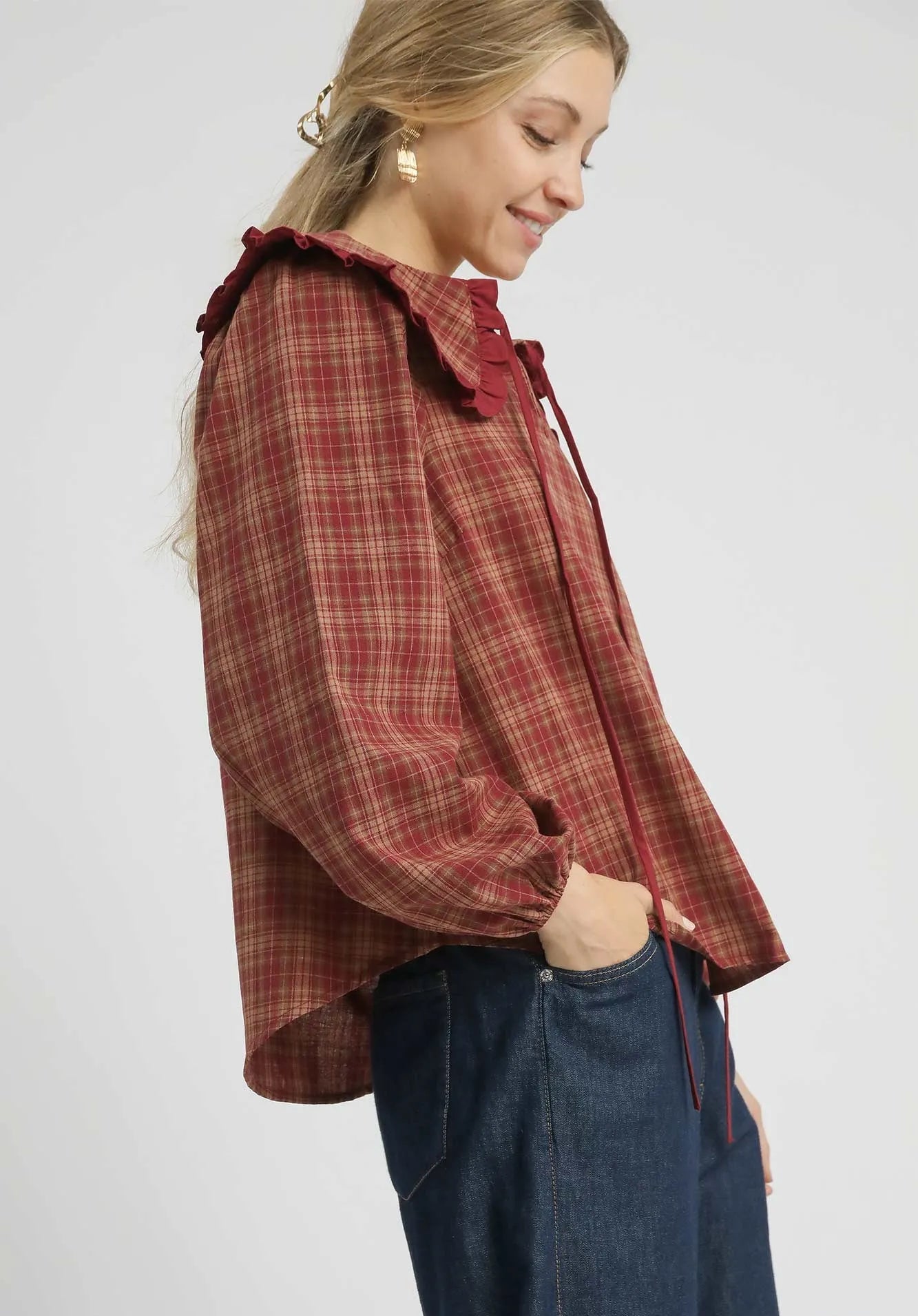 Woman wearing a red plaid shirt with ruffled collar on a white background