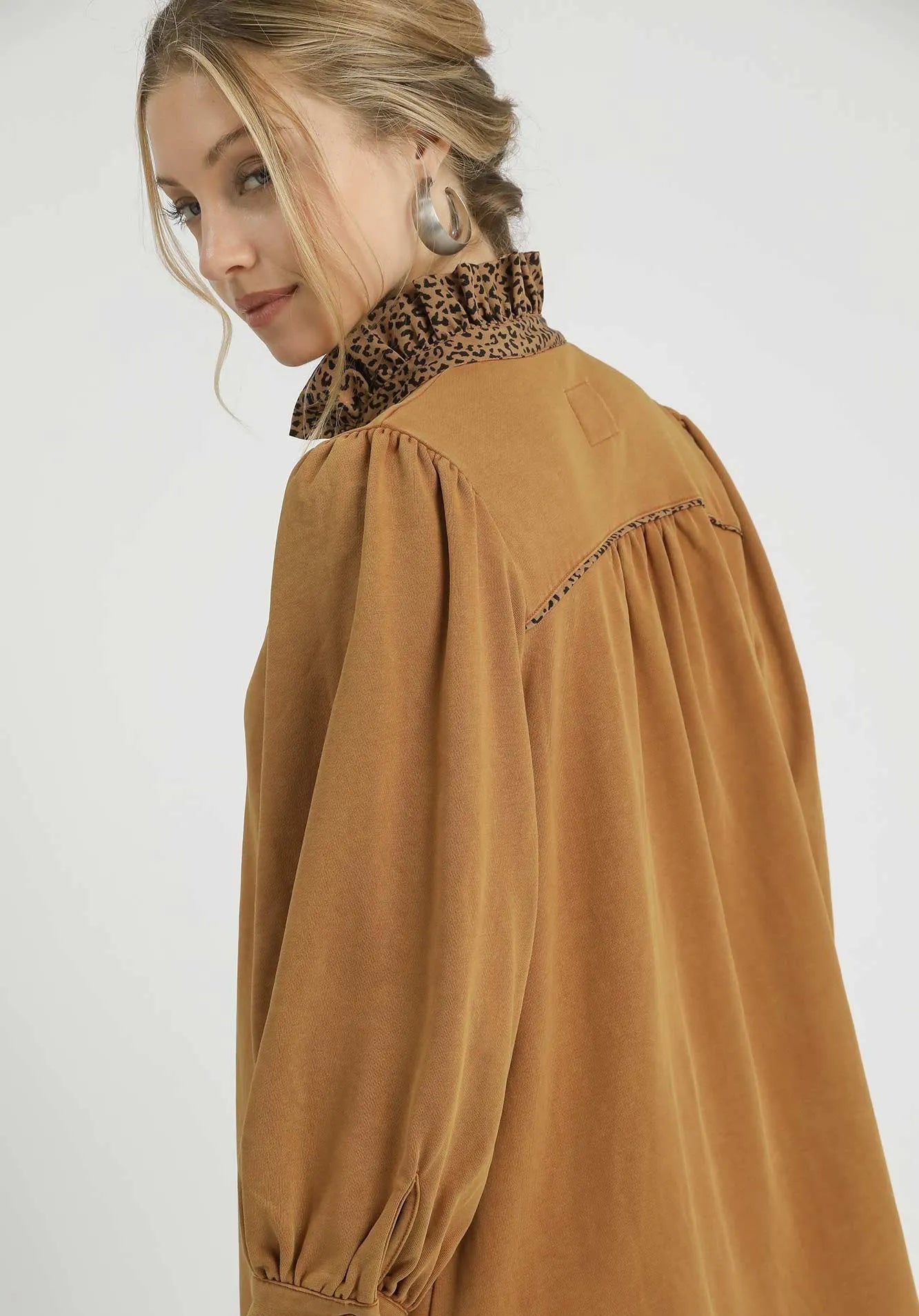 Woman wearing a brown blouse with a leopard print scarf on a white background