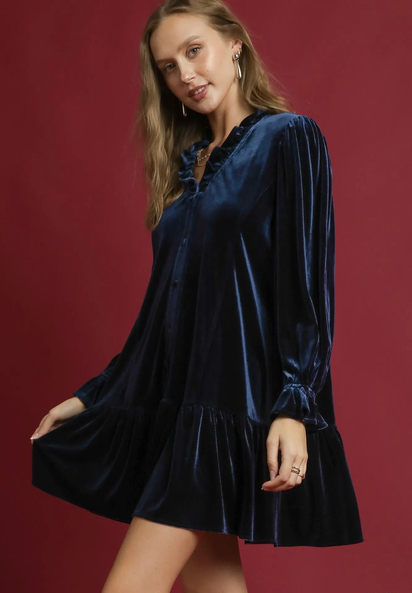 Woman wearing a navy velvet dress against a red background