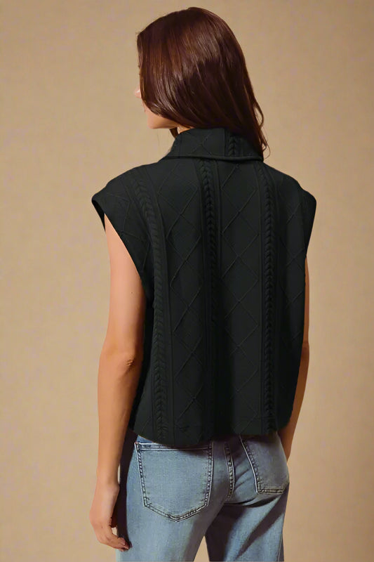 Person wearing a black sleeveless vest with a beige background