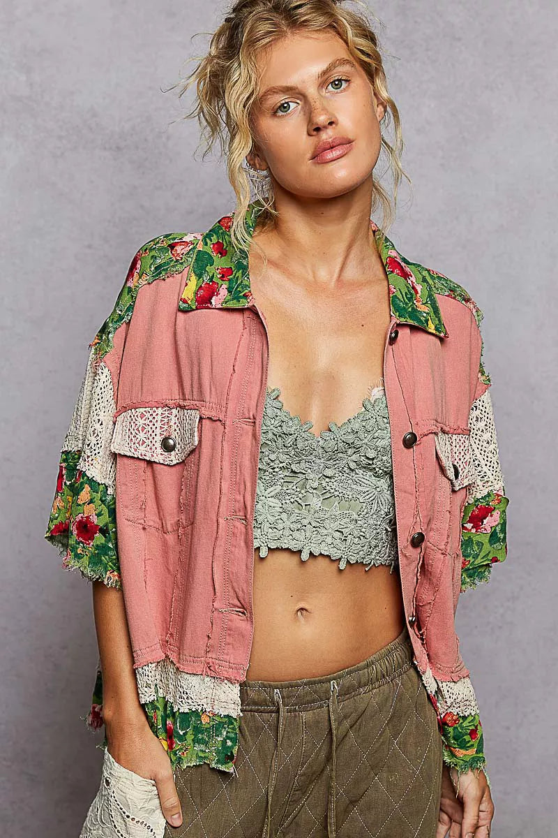Woman wearing a floral jacket over a pink top with a gray background