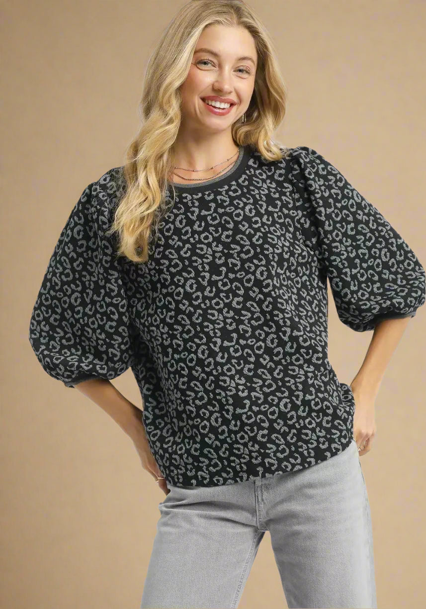 Woman wearing a charcoal leopard print sweater with gray pants on a white background