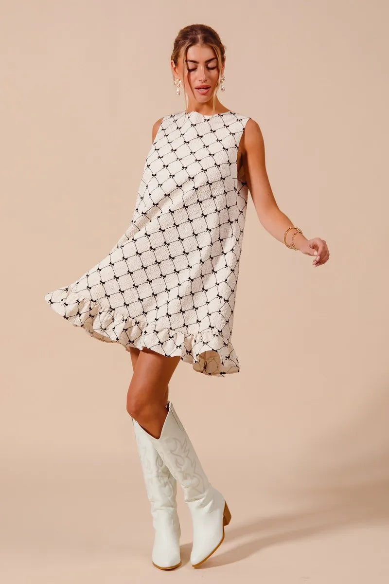 Woman wearing a patterned dress and white boots on a beige background