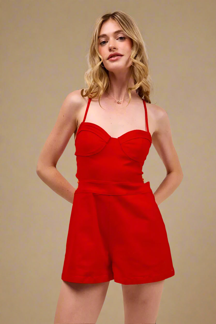 Woman wearing a red romper against a beige background