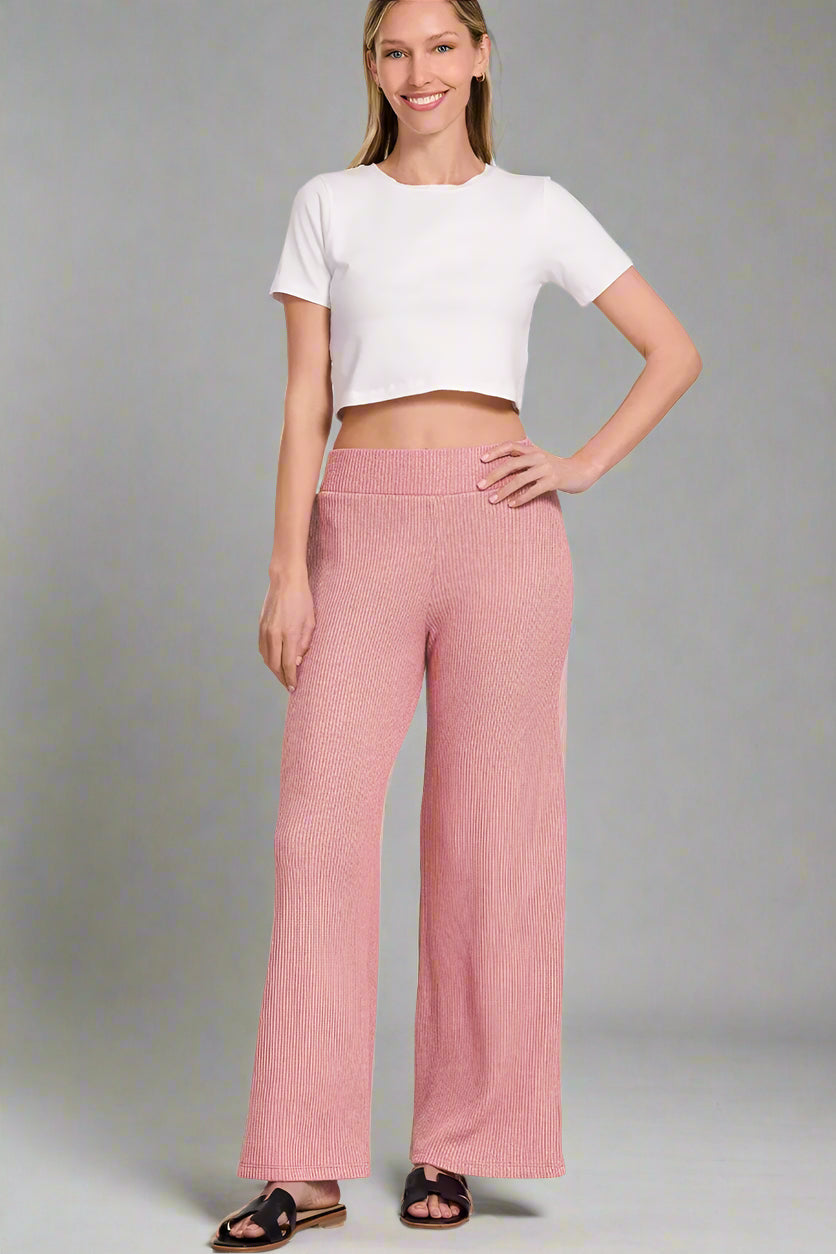 Woman wearing a white top and light rose pants on a white background