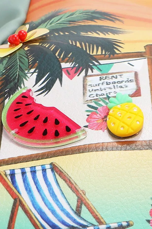Colorful beach-themed items including a watermelon slice, pineapple, and palm leaves on a wooden surface.
