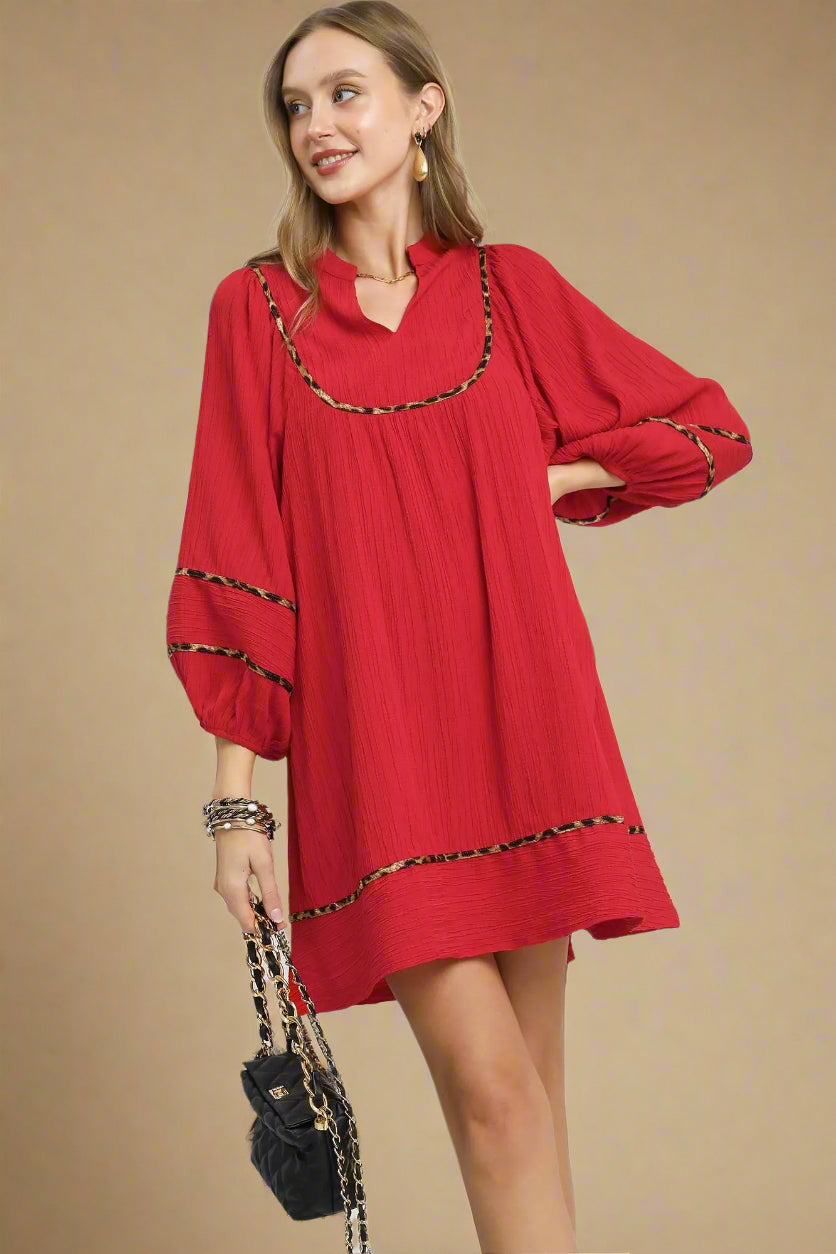 Woman wearing a red dress with leopard print trim on a beige background