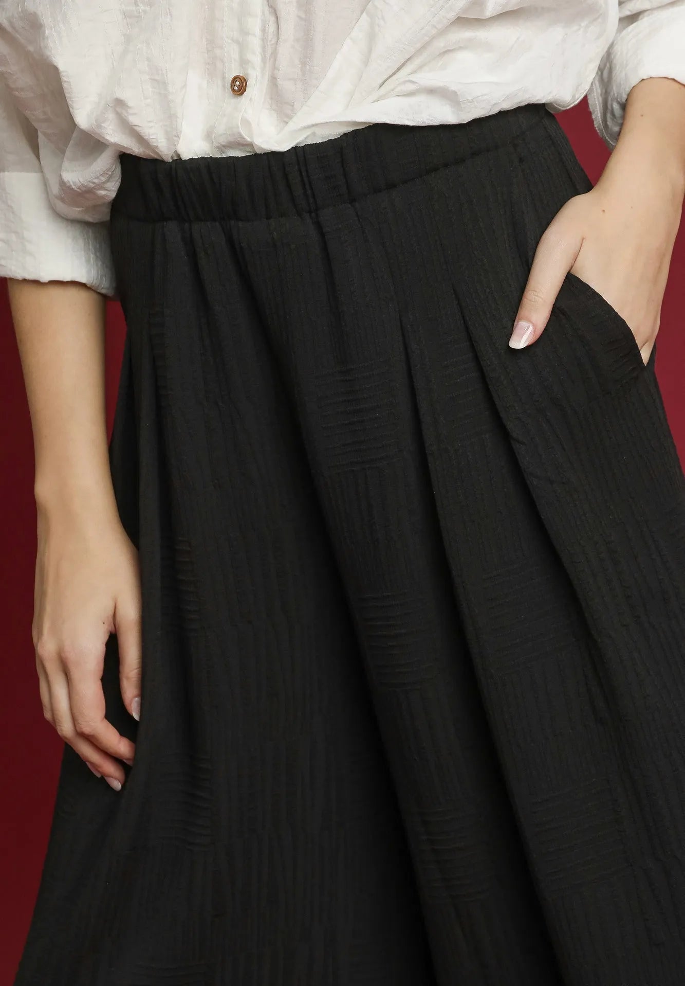 Person wearing a white shirt and black pants on a red background